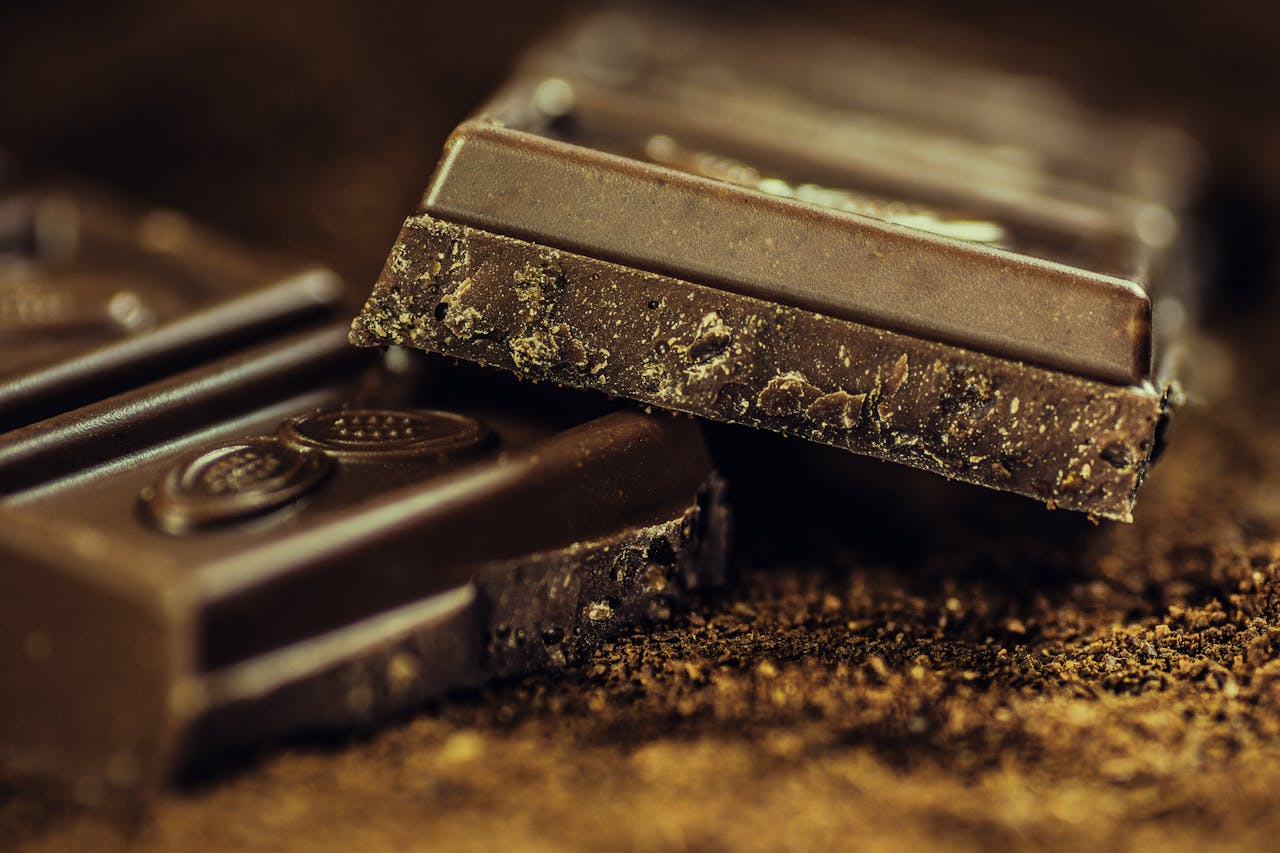 home-hero Macro shot of rich dark chocolate bars sprinkled with cocoa powder, highlighting texture and indulgence.