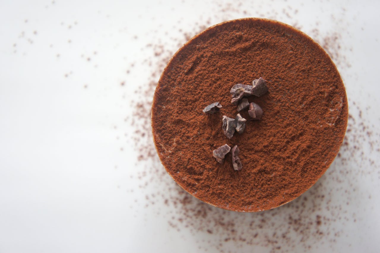 why-choose-us Top view of a rich chocolate dessert dusted with cocoa powder on a white background.